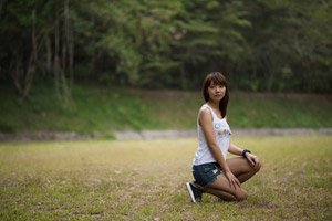 片膝をついてしゃがむタンクトップとショートパンツ姿の女性