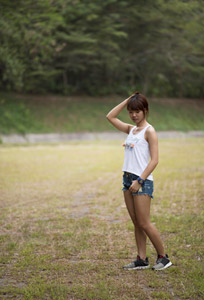 うつむくタンクトップとショートパンツ姿の女性の全身ショット