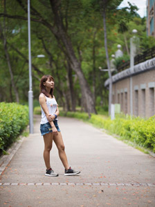 タンクトップとデニムのショートパンツ姿で遊歩道に立つ女性