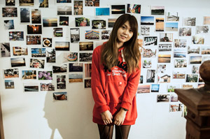 フリー写真 写真が飾られた壁の前に立つ若い台湾人女性