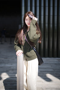 フリー写真 ポールの上に手を置いてスマホをかざす中国人女性