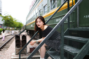 フリー写真 列車の前の昇降階段に座る中国人女性