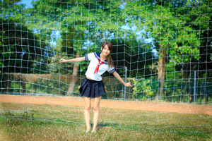 フリー写真 サッカーのゴールネットの前で体を傾ける女子学生