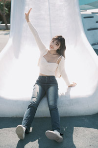 フリー写真 滑り台に座って片手を挙げる台湾人女性