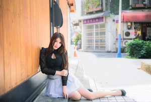 フリー写真 木製の壁に寄り掛かって横座りする台湾人女性