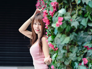 フリー写真 ハイビスカスの壁の前に立つ台湾人女性