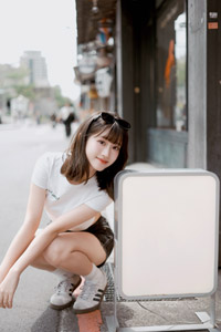 フリー写真 看板の側にしゃがむ台湾人女性