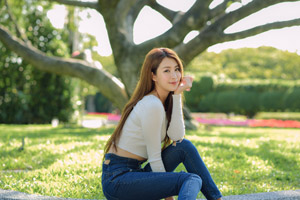 フリー写真 顎に手を当てて花壇の脇に座る台湾人女性