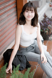 フリー写真 シャッターが閉まった建物の前に座る台湾人女性