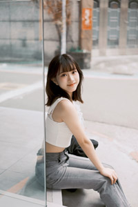 フリー写真 ショーインドーの脇に座るタンクトップ姿の台湾人女性