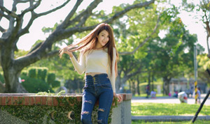 フリー写真 髪を触りながら公園に立つ台湾人女性