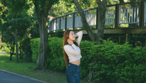 フリー写真 目を閉じながら公園に立つ台湾人女性