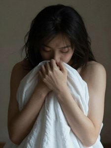 AI画像 シーツに身を包んでうつむくアジア人女性