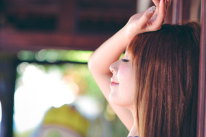 フリー写真 目を閉じて頭の上に手をのせる台湾人女性