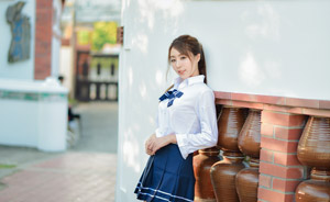 フリー写真 壁にもたれかかって立つ女子学生
