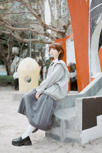 フリー写真 すべり台の縁に座るパーカーとスカート姿の台湾人女性