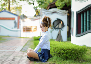 フリー写真 髪の毛を持ち上げながらあぐらをかいて座る女子学生