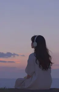 AI画像 ヘッドフォンをつけて夕空を眺めている少女