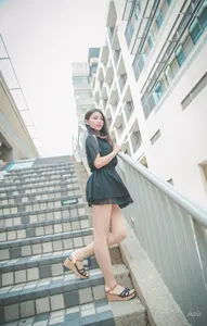 フリー写真 黒色のミニワンピを着て階段の手すりの前に立つ台湾人女性