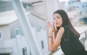 フリー写真 フェンスに肘をついて指を合わせる台湾人女性
