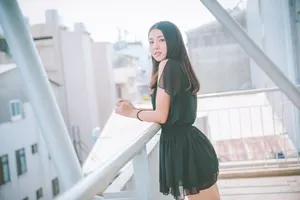 フリー写真 黒色のミニワンピースを着て屋上のフェンスの前に立つ台湾人女性
