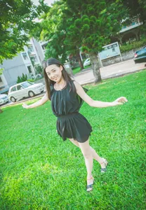 フリー写真 両手を広げて公園の芝生の上に立つ台湾人女性