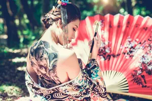 フリー写真 煙管を持つ背中にタトゥーがあるアジア人女性