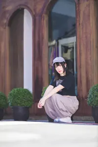 フリー写真 建物の前でしゃがむキャップを被った台湾人女性