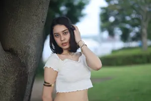 フリー写真 髪を触りながら木の側に立つアジア人女性
