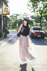 フリー写真 鞄を肩にかけて立つキャップを被った台湾人女性