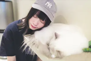 フリー写真 寝ている猫に頬を当てる台湾人女性