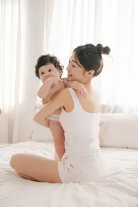 フリー写真 ベッドの上で赤ちゃんを抱くお母さん