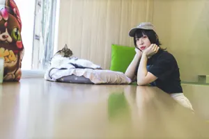 フリー写真 クッションの上の猫と頬杖をつく台湾人女性