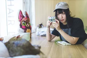 フリー写真 眠っている猫の写真を撮る台湾人女性