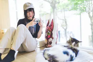 フリー写真 デジカメで猫カフェの猫の写真を撮る台湾人女性
