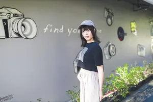 フリー写真 カメラが描かれた壁とキャップを被った台湾人女性