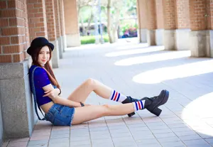 フリー写真 柱にもたれかかって座るポーラーハットを被った台湾人女性