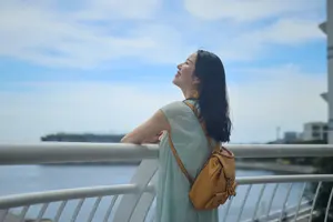 フリー写真 柵の前に立って空を見上げる日本人女性
