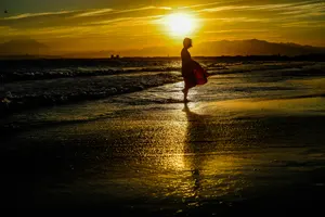 フリー写真 女性のシルエットと夕暮れのビーチ