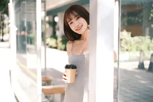フリー写真 紙コップを持ってバス停の柱の側に立つ台湾人女性