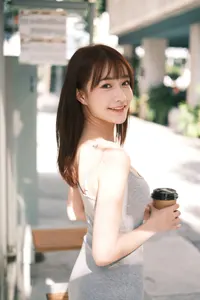 フリー写真 紙コップを持ってバス停に立つグレーのロングワンピ姿の台湾人女性