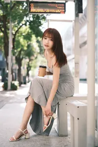 フリー写真 サンダルのストラップを締めながらバス停のベンチに座る台湾人女性