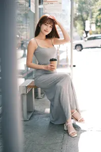 フリー写真 手をかざしてバス停のベンチに座る台湾人女性