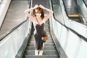 フリー写真 頭の上に手をのせてエスカレーターに乗る台湾人女性