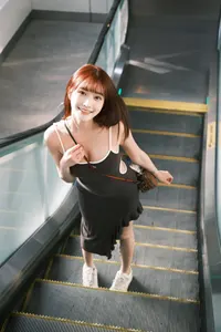 フリー写真 ポーチを肩にかけてエスカレーターに乗る台湾人女性