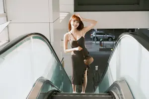フリー写真 頭に手を当ててエスカレーターに乗る台湾人女性